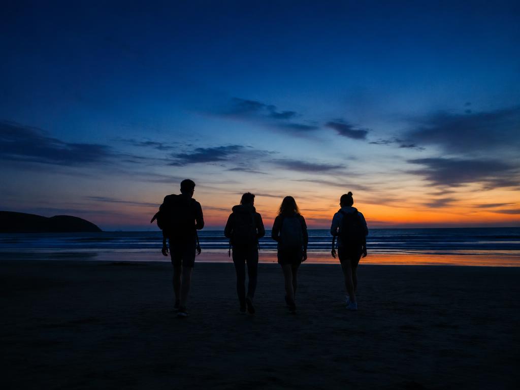 Friends walking to the sea at dusk